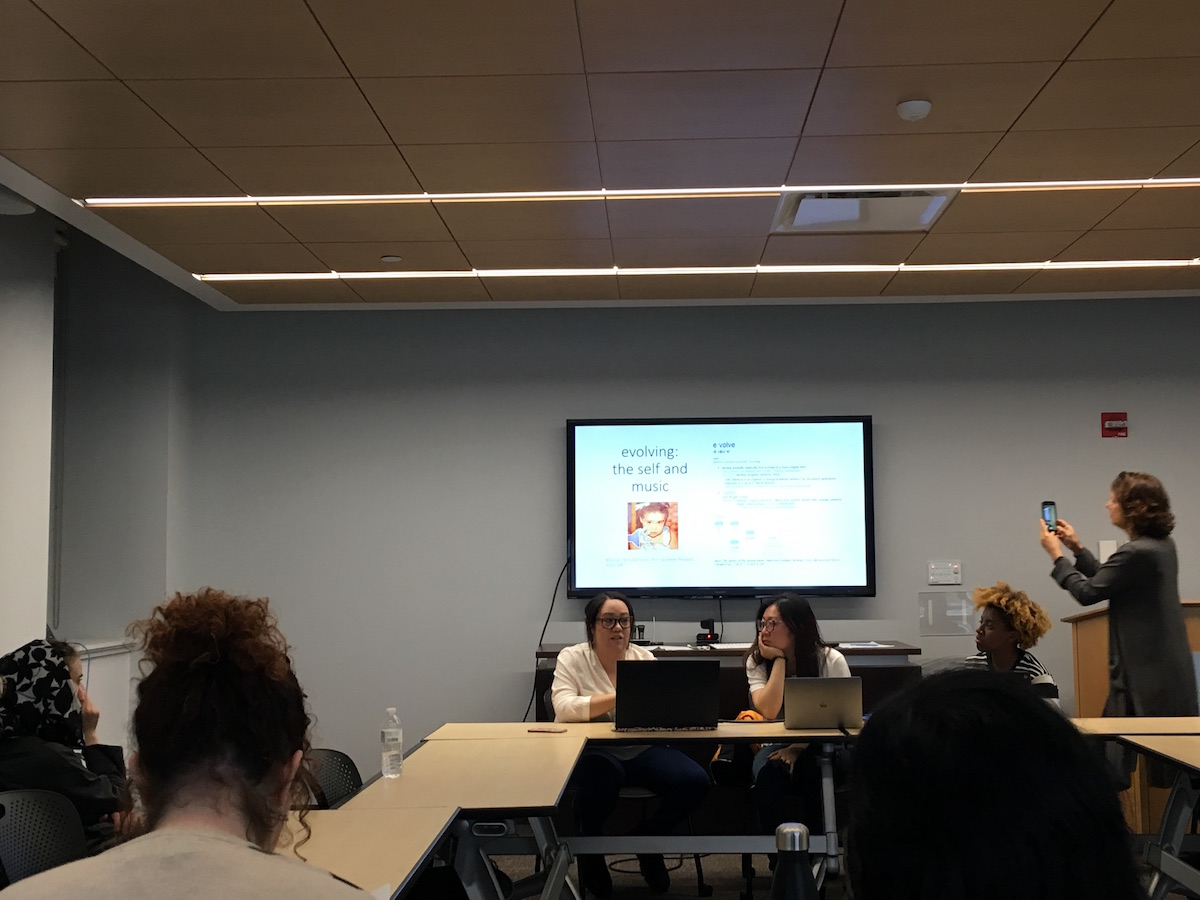 two students sit in front of screen on panel